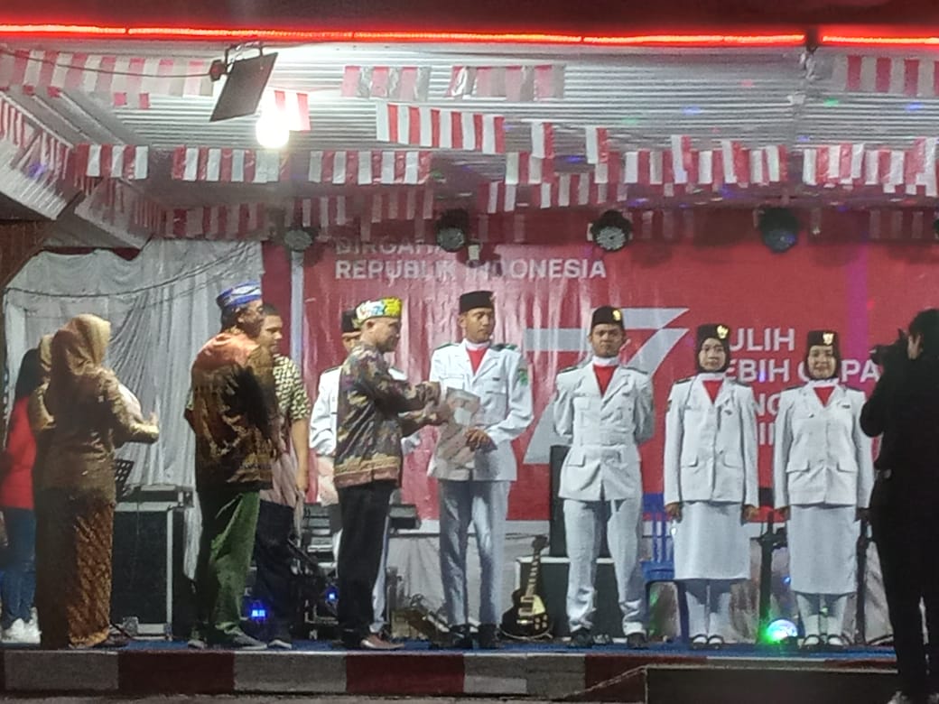Kepala BKAD Kubar, Sahadi SHut MSi menyerahkan piagam penghargaan kepada Paskibra Merah Putih pada Upacara Peringatan HUT ke-77 Kemerdekaan RI di Kecamatan Muara Pahu, Jumat 9 September 2022 malam. (Foto: Dok. Istimewa).